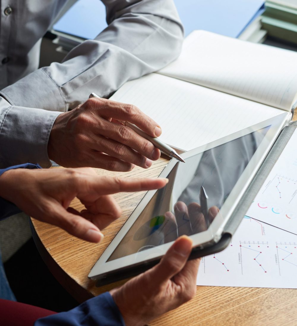 Digital tablet with financial report in hands of business partners